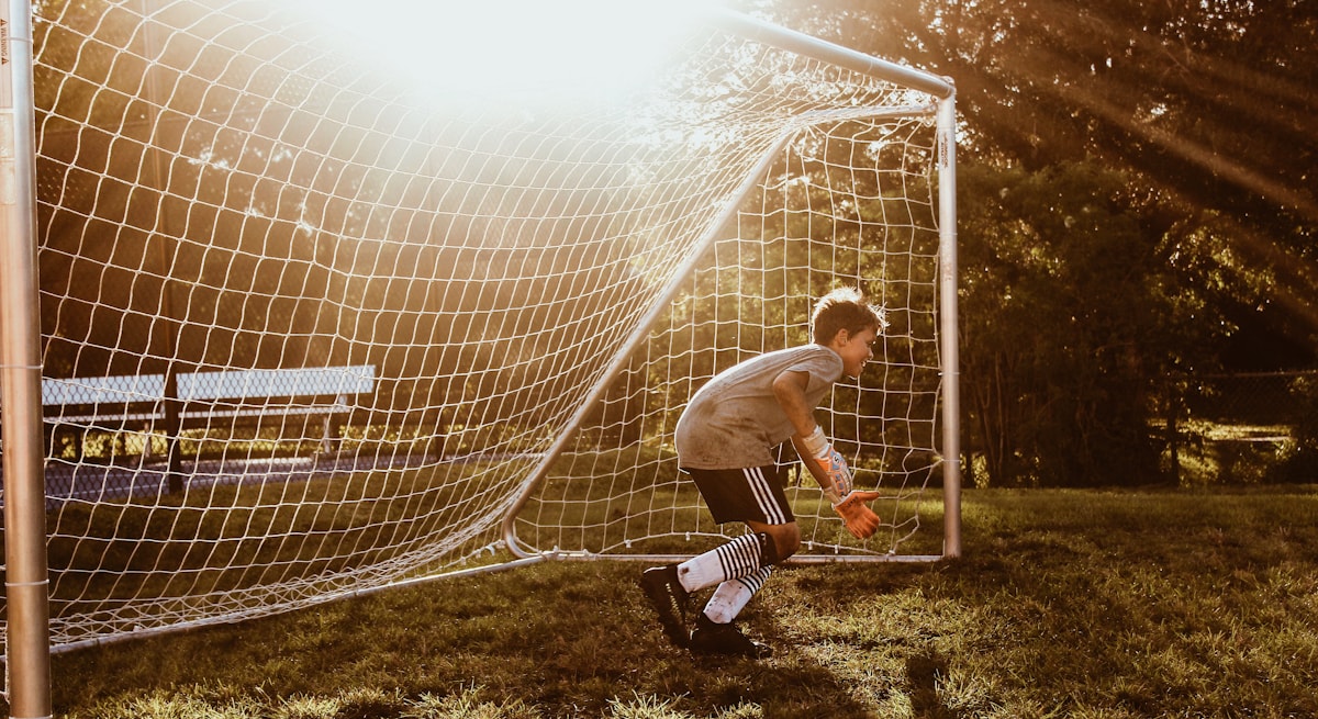 Jeugdkeeper voor een voetbaldoel in het avondlicht